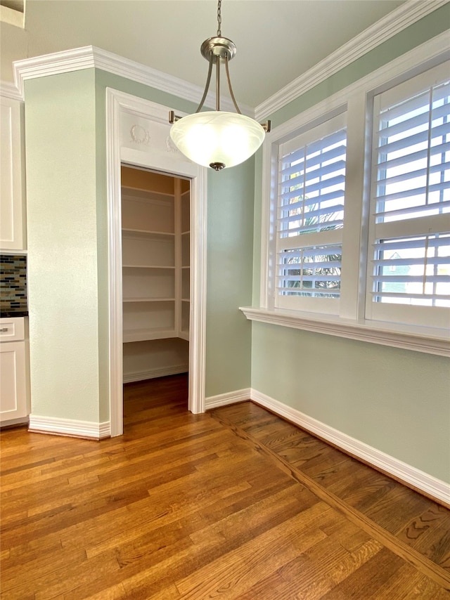 unfurnished dining area featuring crown molding and light hardwood / wood-style floors