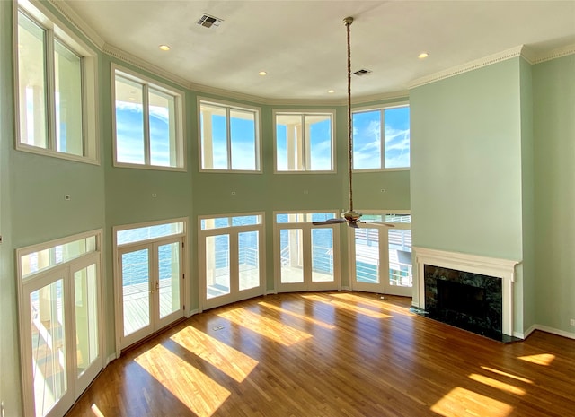 unfurnished living room featuring a fireplace, wood-type flooring, crown molding, ceiling fan, and french doors