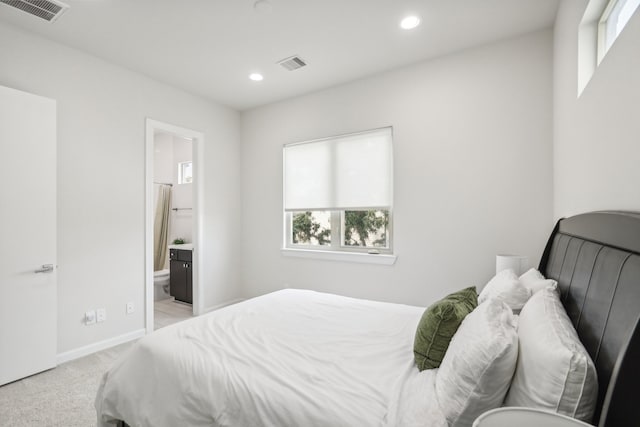 bedroom featuring ensuite bathroom and light carpet