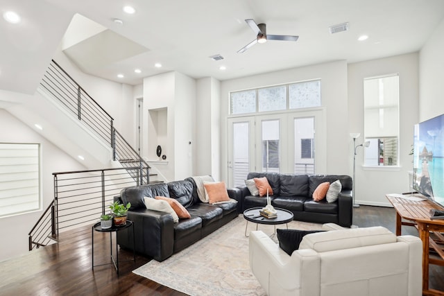 living room with a high ceiling, ceiling fan, and dark wood-type flooring