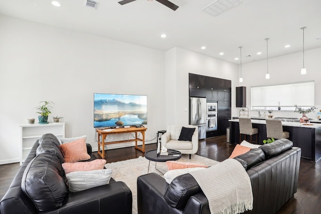 living room featuring ceiling fan, a towering ceiling, and dark wood-type flooring