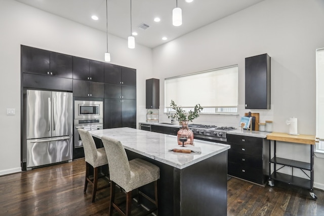 kitchen featuring pendant lighting, a breakfast bar area, dark wood-type flooring, stainless steel appliances, and a center island