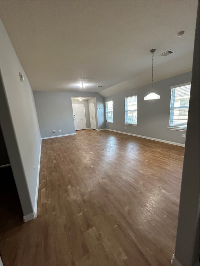 unfurnished living room featuring a wealth of natural light and dark hardwood / wood-style floors