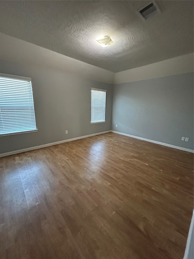 unfurnished room with a textured ceiling and dark hardwood / wood-style floors