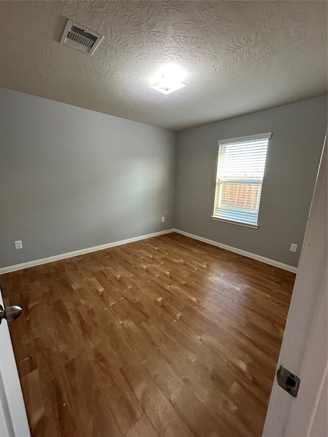 empty room featuring a textured ceiling and hardwood / wood-style flooring