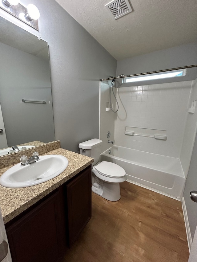 full bathroom featuring a textured ceiling, bathing tub / shower combination, hardwood / wood-style floors, vanity, and toilet