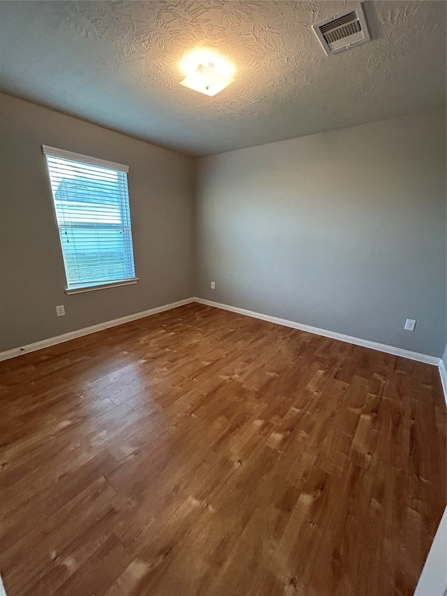 spare room with a textured ceiling and wood-type flooring