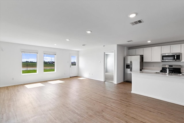 kitchen featuring stainless steel appliances, white cabinetry, hardwood / wood-style flooring, and sink