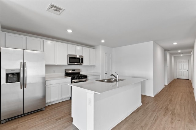 kitchen featuring stainless steel appliances, white cabinets, a kitchen island with sink, and sink