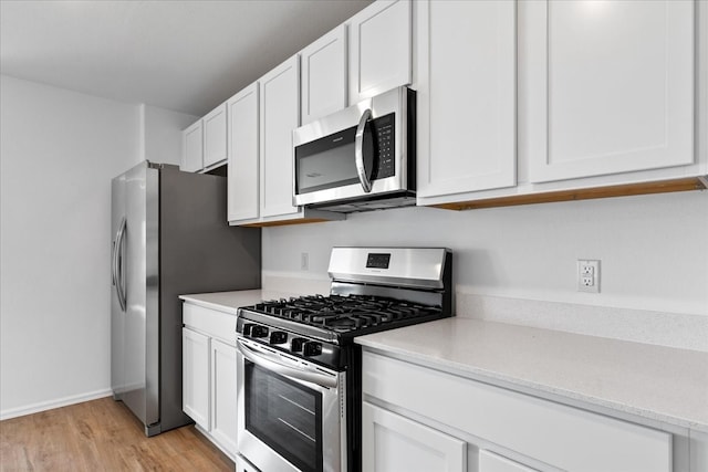 kitchen with stainless steel appliances, white cabinetry, and light hardwood / wood-style floors