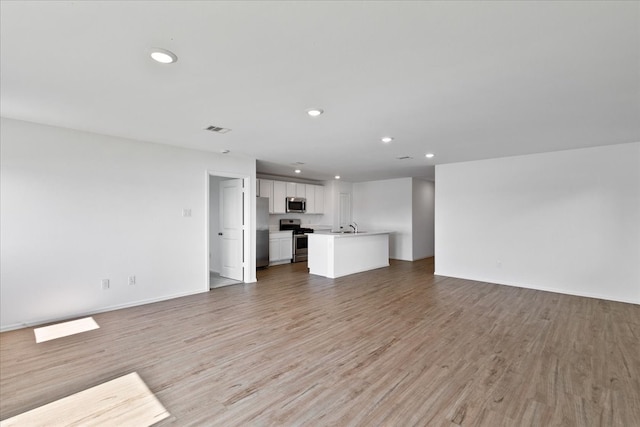 unfurnished living room featuring sink and light hardwood / wood-style floors