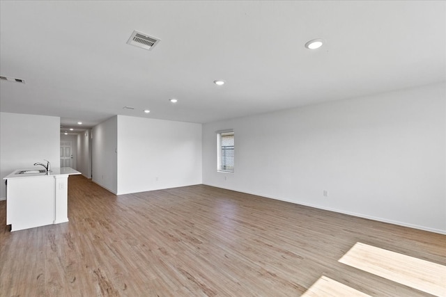 unfurnished living room featuring light hardwood / wood-style flooring and sink