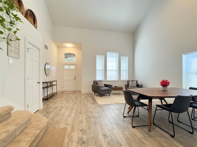 dining space with a high ceiling, light hardwood / wood-style flooring, and a wealth of natural light