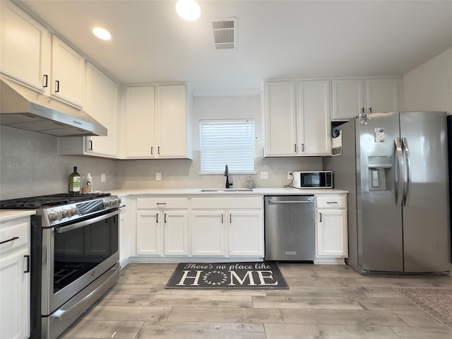 kitchen with appliances with stainless steel finishes, light hardwood / wood-style floors, sink, and white cabinets