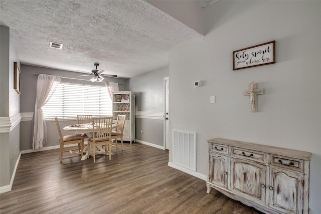 dining space with ceiling fan, a textured ceiling, and dark wood-type flooring