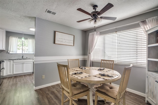 dining area with ceiling fan, a textured ceiling, dark wood-type flooring, and sink