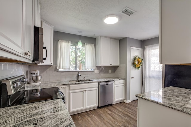 kitchen featuring hanging light fixtures, tasteful backsplash, white cabinetry, stainless steel appliances, and dark hardwood / wood-style floors