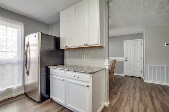 kitchen featuring white cabinets, light stone countertops, stainless steel fridge, and dark hardwood / wood-style floors