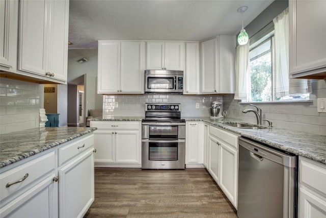 kitchen featuring sink, white cabinetry, appliances with stainless steel finishes, decorative light fixtures, and dark hardwood / wood-style flooring