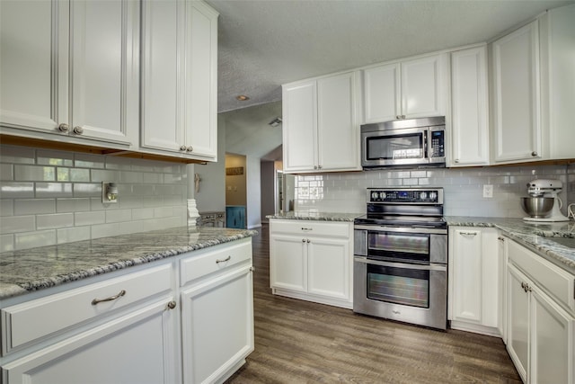 kitchen featuring stainless steel appliances, white cabinets, dark wood-type flooring, and tasteful backsplash