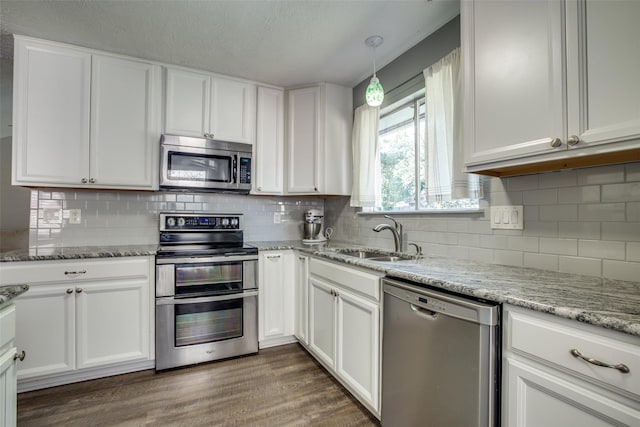 kitchen with white cabinets, appliances with stainless steel finishes, and pendant lighting