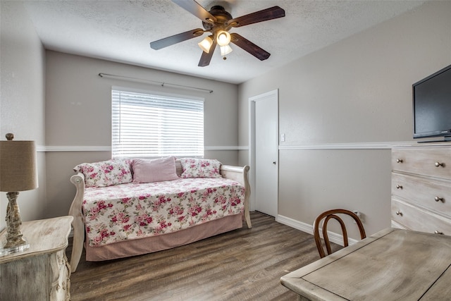 bedroom with ceiling fan, dark hardwood / wood-style floors, and a textured ceiling