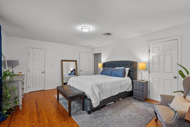 bedroom featuring baseboards, visible vents, and wood finished floors
