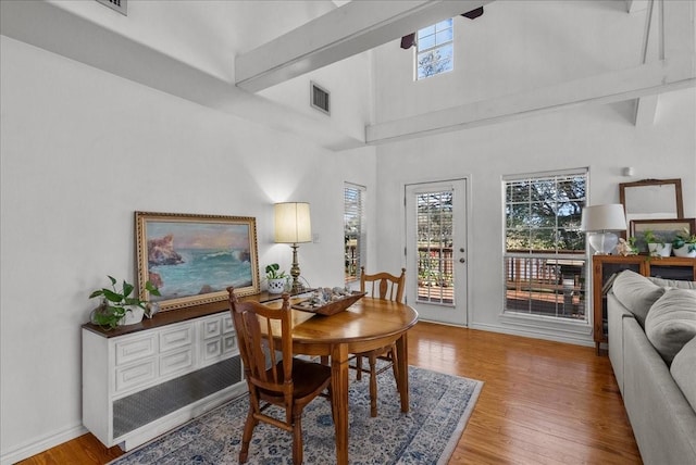 dining space with wood finished floors, baseboards, a high ceiling, and visible vents