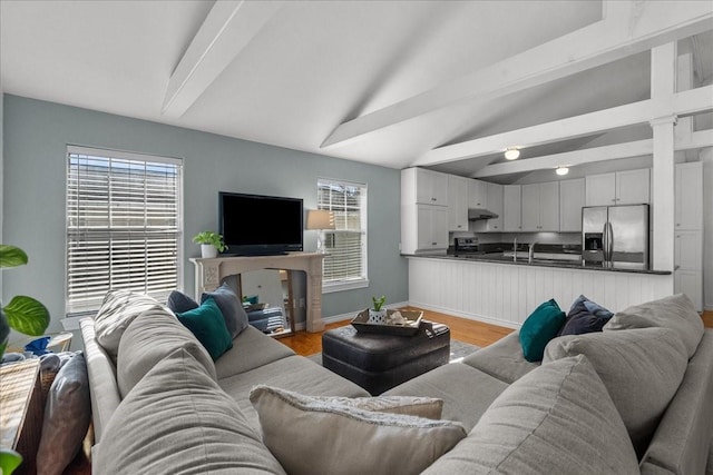 living area with baseboards, plenty of natural light, lofted ceiling with beams, and light wood-style flooring