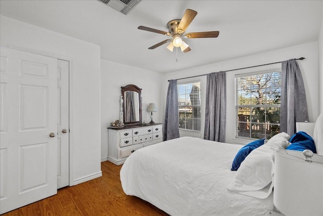 bedroom with baseboards, ceiling fan, wood finished floors, and visible vents