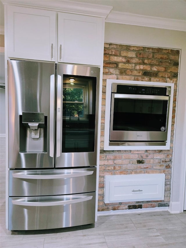 interior details featuring stainless steel appliances, ornamental molding, and white cabinets