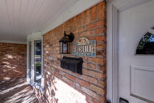 property entrance featuring a porch and brick siding