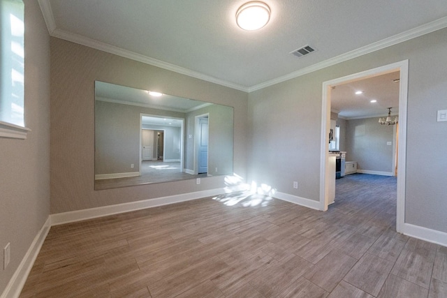 unfurnished room with ornamental molding, visible vents, baseboards, and wood finished floors