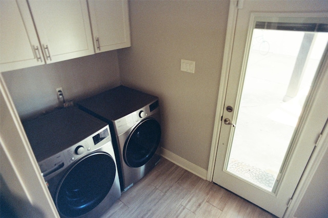 laundry area featuring cabinet space, light wood-style flooring, baseboards, and washing machine and clothes dryer