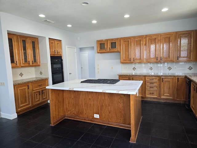 kitchen featuring decorative backsplash, dark tile patterned flooring, a kitchen island, light stone countertops, and black appliances