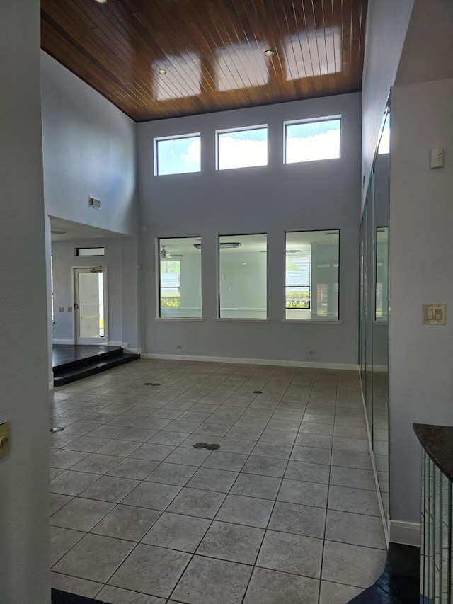 spare room featuring a towering ceiling, light tile patterned floors, and wooden ceiling