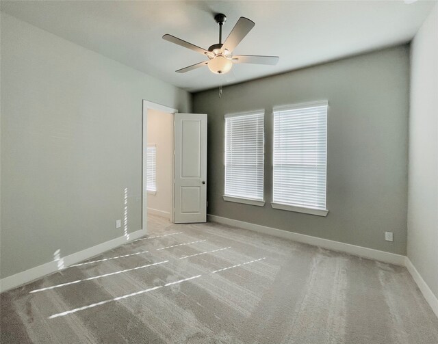 carpeted empty room with ceiling fan and plenty of natural light