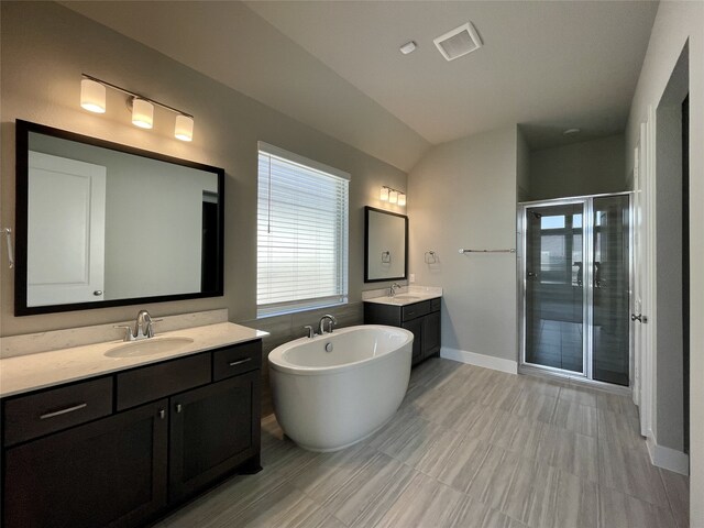 bathroom with vanity, shower with separate bathtub, and lofted ceiling