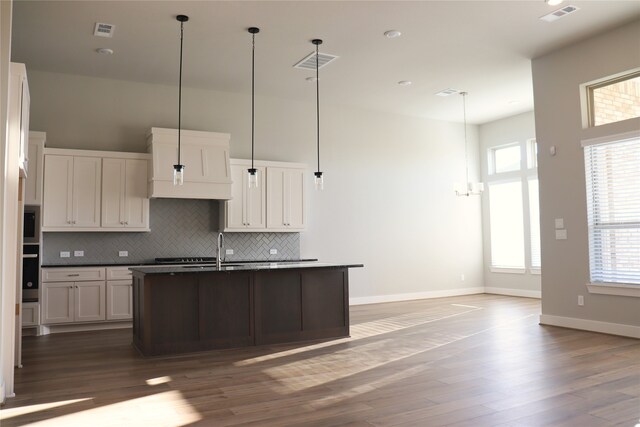 kitchen with white cabinets, a kitchen island with sink, and dark wood-type flooring