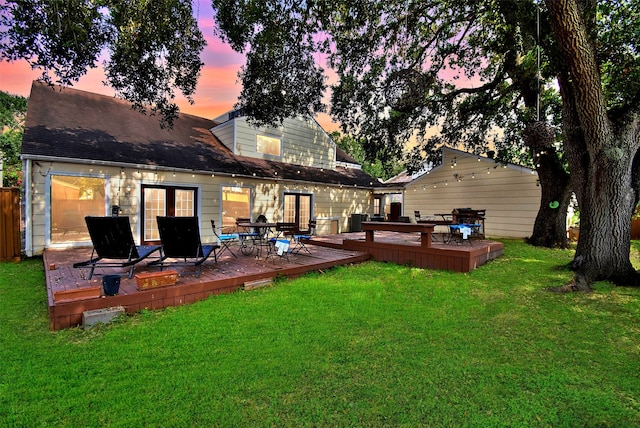 back house at dusk featuring a deck and a yard