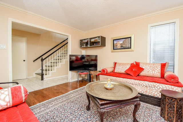 living room with light wood-type flooring, a textured ceiling, and ornamental molding