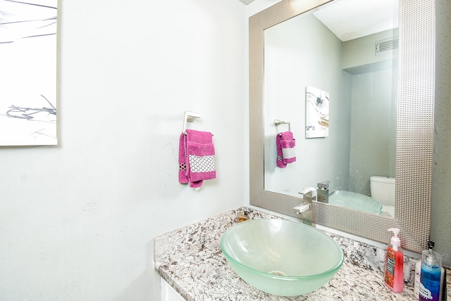 bathroom featuring a textured ceiling, vanity, and toilet