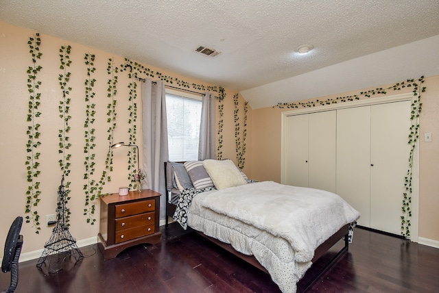 bedroom with a textured ceiling, a closet, and dark hardwood / wood-style floors