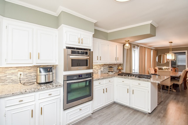 kitchen with white cabinets, kitchen peninsula, stainless steel appliances, light hardwood / wood-style floors, and decorative backsplash