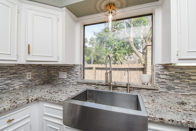 kitchen with light stone countertops, tasteful backsplash, sink, and white cabinets