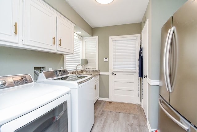 laundry area with cabinets, light hardwood / wood-style floors, sink, and washer and dryer