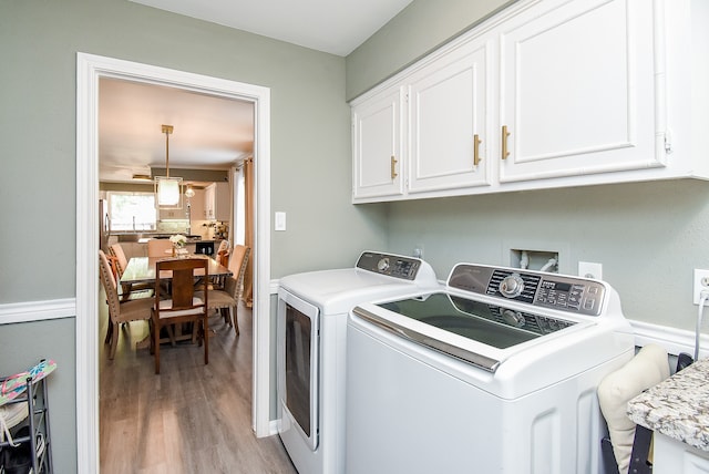 clothes washing area featuring separate washer and dryer, cabinets, and light hardwood / wood-style floors