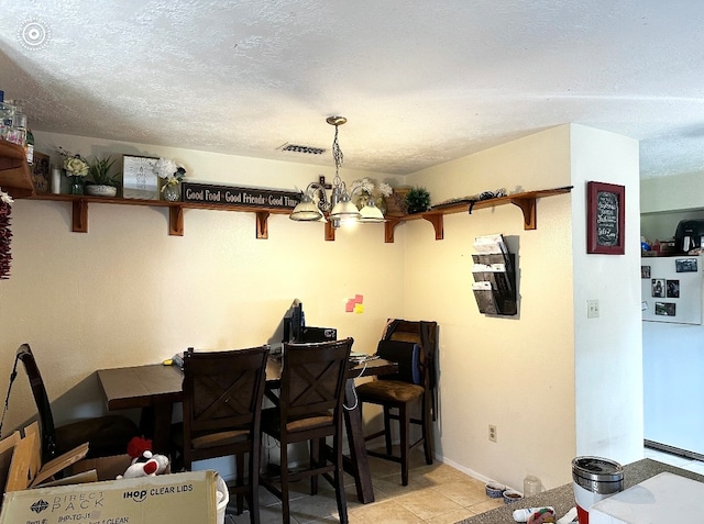 tiled dining room with a notable chandelier and a textured ceiling