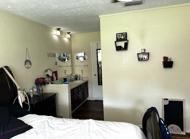 bedroom featuring a textured ceiling, dark hardwood / wood-style floors, and sink