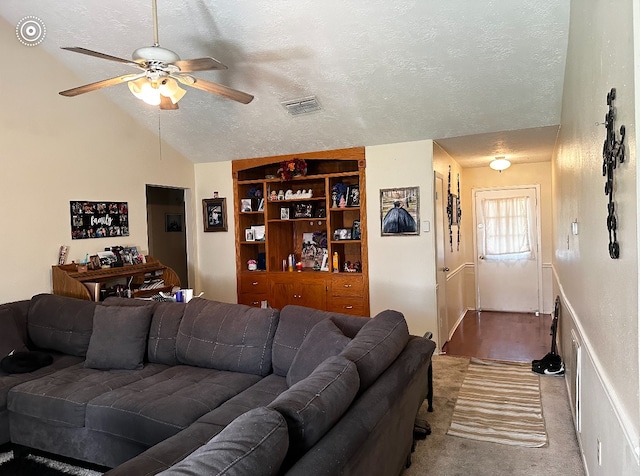 living room featuring ceiling fan, a textured ceiling, light carpet, and vaulted ceiling